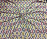 Colorful ikat pattern woven fabric in shades of red, yellow, and blue, spread out and twisted in the center to showcase the intricate design, 45-inch width, from PAVANKUMARWEAVES."