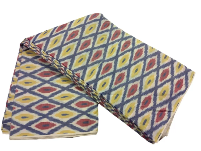 Colorful ikat pattern woven fabric in shades of red, yellow, and blue, spread out and twisted in the center to showcase the intricate design, 45-inch width, from PAVANKUMARWEAVES."