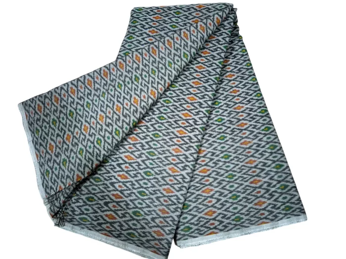 cotton silk fabric with a traditional ikat pattern featuring multicolored diamond motifs arranged in a symmetrical design."