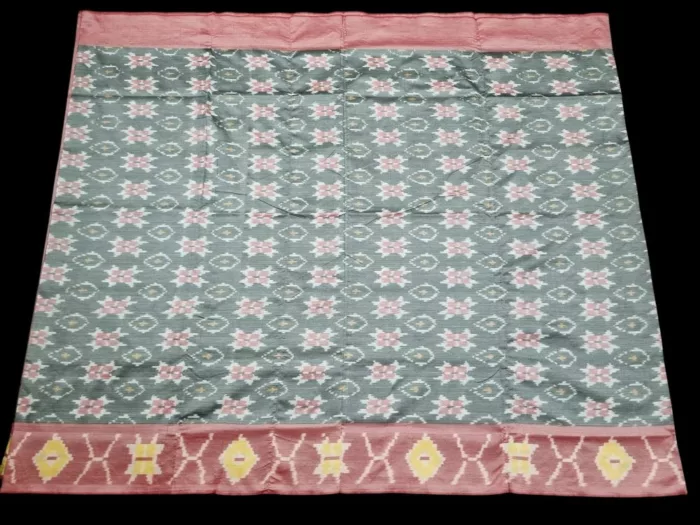 Photo of a handwoven semi-silk Pochampally saree featuring vibrant ikat diamond and temple motifs, showing the broad patterned border and pallu alongside a matching blouse piece.